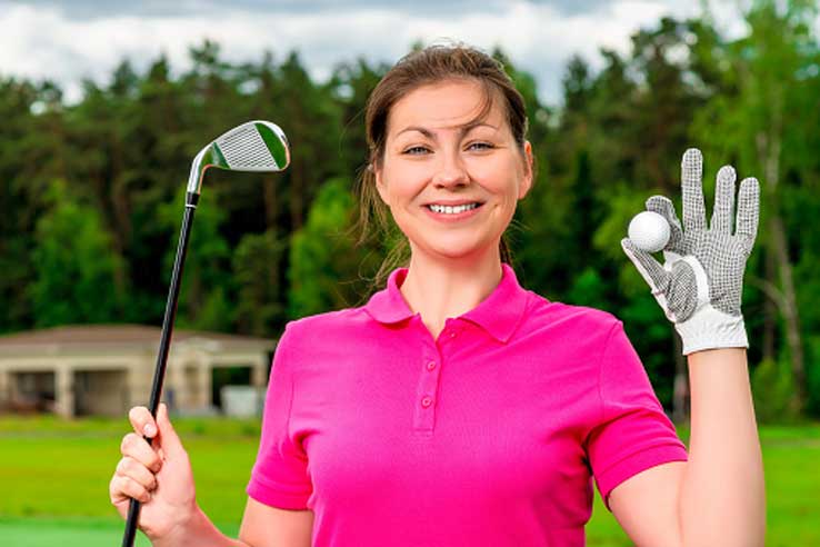 Woman holding golf club and ball