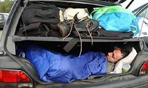  A person asleep in the trunk of a vehicle.