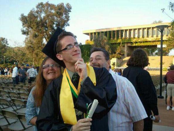 Student in commencement regalia with family